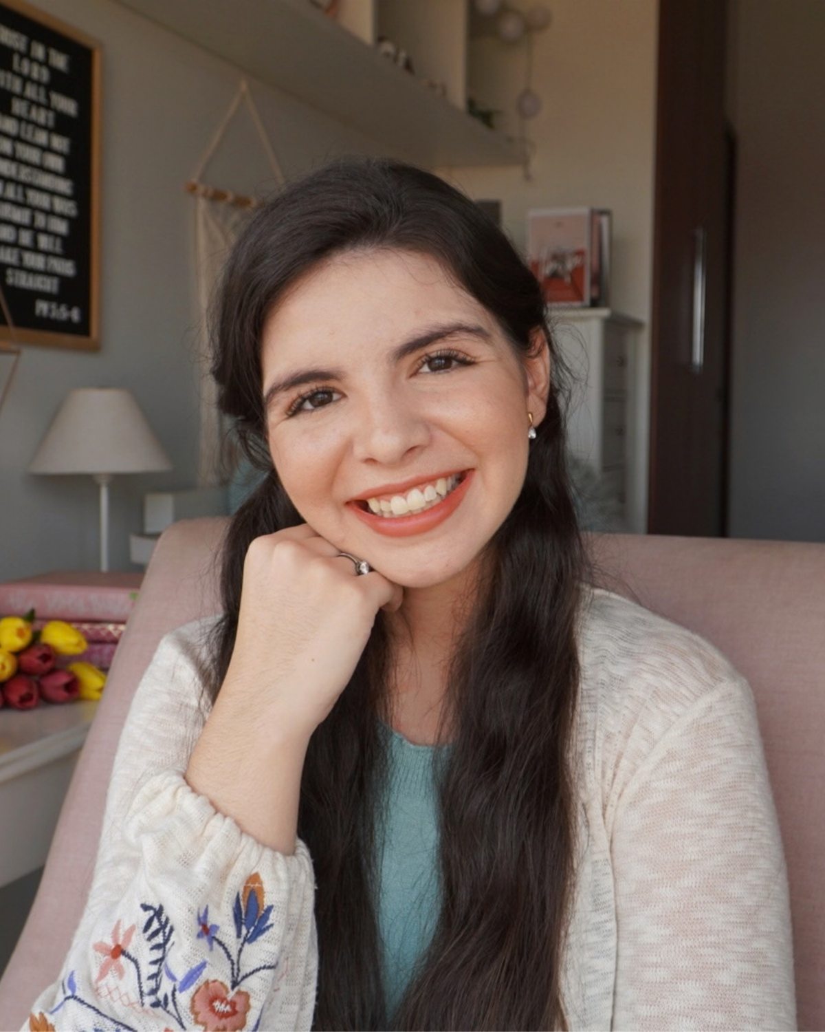 Rebeca Salazar sorrindo, sentada em uma poltrona rosa
